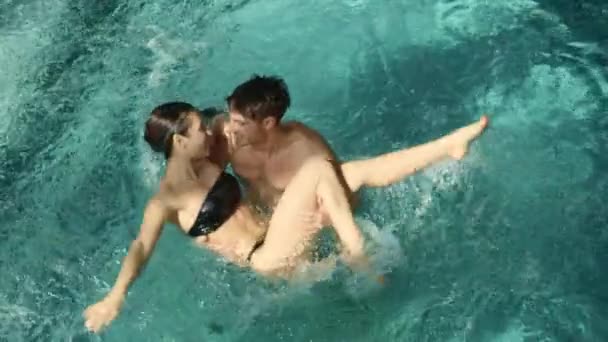 Romantický pár objímající se v bazénu. Muž drží ženu v náručí v termálním bazénu — Stock video