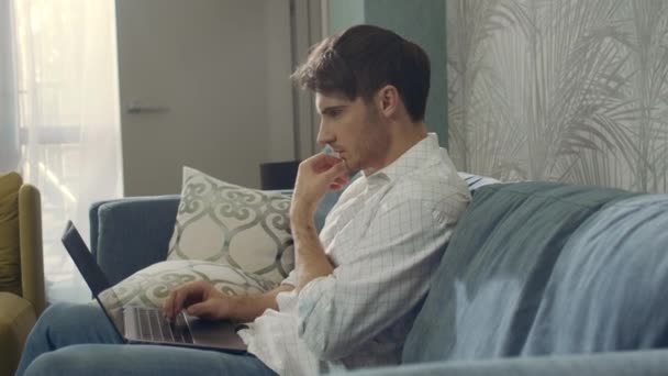 Skupiony człowiek patrzący na ekran laptopa w domu. Przemyślany facet pracujący w hotelu komputerowym — Wideo stockowe