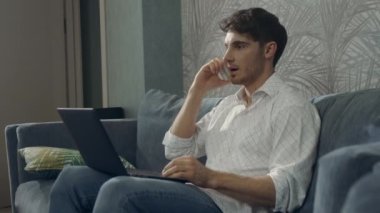 Kendine güveni tam bir adam aynı anda dizüstü bilgisayar kullanıyor. Akıllı telefon bilgisayarıyla çalışan adam.