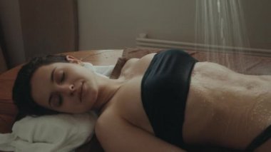 Çekici bir bayan tatil köyünde dinleniyor. Bikini kadın kaplıcada su masajı yaptırıyor..