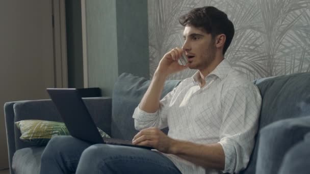 Skupiony człowiek pracujący zdalnie na laptopie. Facet korzystający ze smartfona i komputera. — Wideo stockowe
