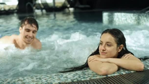 Piękne spotkanie pary w basenie spa. Guy i dziewczyna relaks w jacuzzi wewnątrz — Wideo stockowe