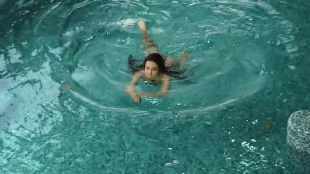 Розслаблена жінка насолоджується відпочинком у спа. Чарівна дівчина плаває в критому басейні . — стокове відео