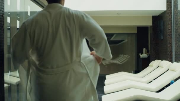 Przystojniak leży na leżaku w spa. Sportowy facet relaksujący się we wnętrzu ośrodka. — Wideo stockowe