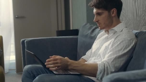 Wütender Kerl schlägt Laptop drinnen. Böser Mann arbeitet im Hotelzimmer am Computer. — Stockvideo