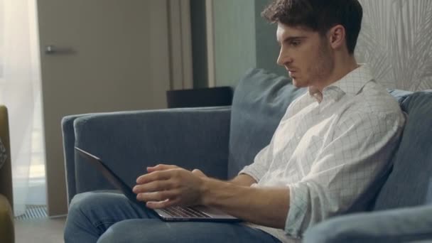 Slechte vent die binnen met de computer werkt. Boze man berichtgeving laptop in hotelkamer. — Stockvideo
