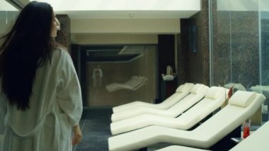 Spa merkezinde bornozunu çıkaran seksi kadın. Güzel kız güvertede dinleniyor..