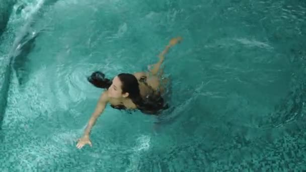 Menina bonito piscina termal flutuante no spa de luxo. Mulher bonita nadando nas costas. — Vídeo de Stock
