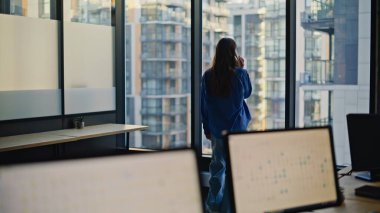 Ciddi bir kadın patronun ofis penceresinde cep telefonunu araması. Zarif kıyafetli esmer iş kadını iş için akıllı telefon kullanıyor. Yöneticinin elinde cep telefonu olması olumlu bir konuşma. 