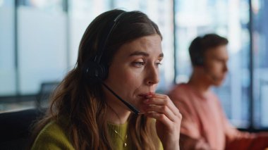 Online servis portresi hazırlayan yardımcı uzman bir müşteri. Kulaklık takan destek operatörü soruları yakından cevaplıyor. İş ortamında müşteriye uzaktan yardım eden dost bir danışman.