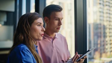 Kapanış şirketi yöneticileri, gökdelenlerin arka planında pencerenin yanında duran işleri konuşuyorlar. Tabletteki inşaat projesini analiz eden iki mimar. İçeride strateji tartışan birkaç meslektaşıma ilham verdim. 