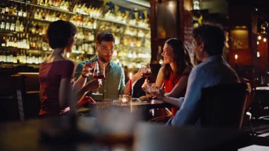 Grup arkadaşları modern şehir restoranında şarap içiyor. Mutlu genç insanlar kadehlerini tokuşturarak hafta sonu dostça buluşmalarının keyfini çıkarıyorlar. Gülümseyen erkekler, kadınların rahatça toplandığı karanlık bar içleri..