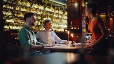 Modern restoranda flört eden iki romantik çift. Bir çift güzel kadın, hoş bir barda gülümseyen adamlarla akşam toplantısına geldi. Karanlık Kafe 'de tanıdığın mutlu genç insanlar. Takılma konsepti.