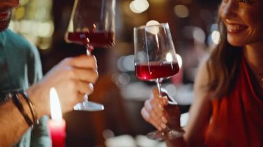 Genç çift, akşam yemeğinde yakın restoranda kadeh tokuşturuyor. Barda romantik bir gece buluşmasında kırmızı şarap içen gülümseyen kadın. Sevgili sevgili el ele tutuşur güzel sevgili aşktan zevk alır.