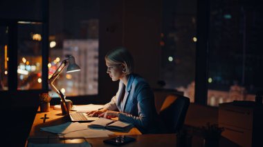 Aşırı mutlu broker dizüstü bilgisayar görünümlü gece işyerinde harika haberler okuyor. Heyecanlı iş kadını akşam ofisinde online zaferi kutluyor. Mutlu bir kadın para kazanmaya başlar. El kol hareketi yapar. 