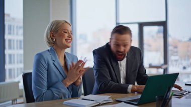 Heyecanlı ortaklar, hafif ofisteki dizüstü bilgisayarlı ekranda sevinçten havalara uçuyor. Cam duvar işyerinde iş başarısını kutlayan mutlu iki meslektaşım. Duygusal iş arkadaşları beş kişiye başarıyı tattırıyor