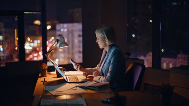 Aşırı yüklü bir kadın karanlık şirket işyerinde geç saate kadar çalışıyor. Yorgun iş kadını cep telefonunu kontrol ediyor. Dizüstü bilgisayarı kapatıyor. Fazla mesai yapmaya istekli değil. Yorgun bayan, sıkı çalışma saatlerini bitirin. 