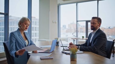 Modern panoramik iş yerinde birlikte çalışan odaklanmış finansal analistler. Sarışın iş kadını şirket içi bürodaki meslektaşlarına belge dağıtıyor. Başarılı işbirliği kavramı 