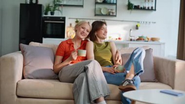 Lgbt çifti birlikte dinleniyor. Gülümseyen kızlar kahve içip televizyon seyrediyorlar. Evde televizyon izleyen genç kadınlar sarılıp yatıyorlar. İki mutlu arkadaş film haftasonunda takılıyorlar. 