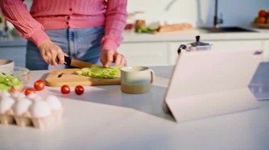 Ev hanımı mutfak bıçağıyla malzemeleri dilimlerken elini yakına koyar. Bayan şef tabletten sabah programı izliyor. Tezgahta duran kız akıllı bir aletle salata pişiriyor. Sarışın kadın ev rutinini seviyor.