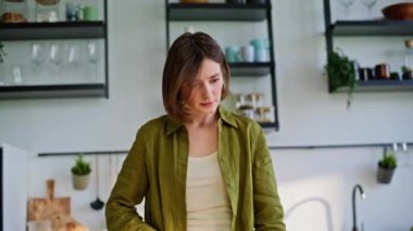 Daire mutfağında sebze doğrayan sabah kadını. Yeşil gömlekli çekici bayan bilgisayardan dijital tarif okuyor. Çağdaş mutfakta yemek pişirmekten hoşlanan bir kız. 