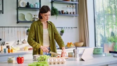 Dans eden esmer, sağlıklı yemek hazırlıyor. Sıcak mutfakta en sevilen şarkı boyunca vücut hareket ediyor. Tasasız neşeli kadın kahvaltı hazırlayan müzik dinliyor. Gülümseyen bayan tek başına lezzetli vejetaryen kasesi yapıyor. 
