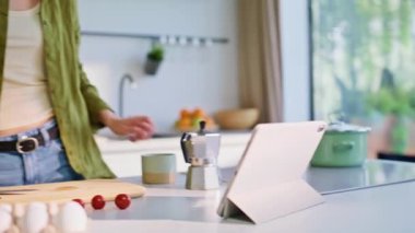 Kızların parmak çevirme cihazı mutfak tezgahında sütlü sabah kahvesinin keyfini çıkarıyor. Kahvaltını yapan gülümseyen kadın, sıcak mutfakta tablette video seyrediyor. Rahat bayan sıcak bir şeyler yudumluyor.