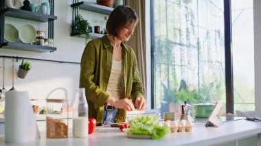 Esmer kız bilgisayarda video tarifi arıyor. Sağlıklı malzemelerle yemek hazırlıyor. Sabahları mutfakta tablet kullanan bir kadın kahvaltı hazırlıyor. Bayan hafif mutfakta alet seyrediyor. 