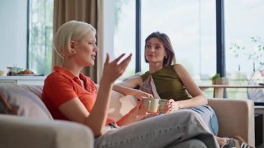 Sohbet eden kankalar kanepenin iç tarafında çay içiyorlar. Sakin kadınlar kahveyi yudumlarken rahat bir dairede hoş sohbetler ediyorlar. İki kız günlük haberleri tartışıyor. İnsanların yaşam tarzı 