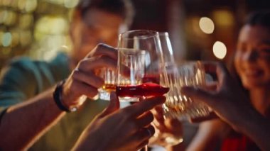 Akşam barında bardakları tokuşturup rahatlayan insanlar yakın çekim yapıyorlar. Mutlu genç arkadaşlar kaygısız gece buluşmasında birlikte alkol içiyorlar. Gülümseyen milenyumlar gece kulübünde arkadaşça takılmanın keyfini çıkarıyorlar..