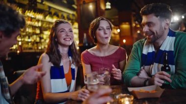 Spor barında bira içen mutlu arkadaşlar. Gülümseyen gençler bardak tokuşturup hafta sonları birlikte maç izliyorlar. Kaygısız arkadaşlar abur cubur yer, alkol içerler.