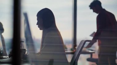 Bilişim uzmanları, bilgisayarlarda eşzamanlı çalışan siluetler kodluyorlar. Konsantre insanlar klavyede veri kontrolü yapan senaryolar yazıyorlar. Proje atamalarını tamamlayan profesyonellerle dolu bir ofis.