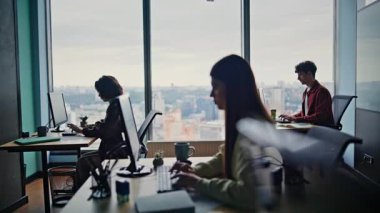 Programcı siluetleri kodlayan bilgisayarlar geniş bir çalışma alanında birlikte oturuyorlar. Klavye yazıp rapor yazan odaklanmış insanlar. Ofis çalışanları modern şehir çalışma alanındaki projeyi tamamlıyorlar