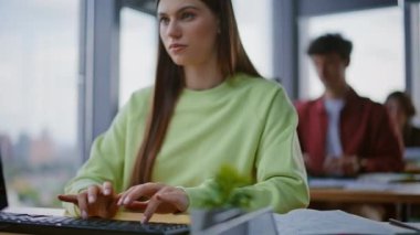 Şirket ofisinde çalışan kadın elleri klavyeyi kapatıyor. Üç öğrenci panoramik pencere binasında bilgisayar kullanarak masalarında oturuyor. Çağdaş çalışma alanındaki çevrimiçi görevlerle meşgul meslektaşlar