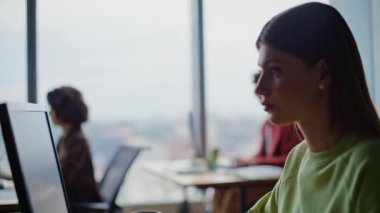 Açık panoramik sınıfta bilgisayar başında programlama eğitimi alan üniversite öğrencileri. Hevesli bir kadın dijital teknolojileri yakından inceliyor. Klavye yazma projesine odaklanmış kadın