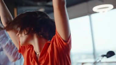 Yakın plan rahatlamış kadın dans ediyor arkadaşlarıyla eğleniyor. Mutlu neşeli takım modern ofis partisinin tadını çıkarıyor. Şarap kadehleriyle gülümseyen meslektaşlar kutlama için cesetleri bir araya getiriyorlar.