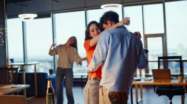 İş arkadaşları panoramik ofis partisinde romantik dansın keyfini çıkarıyorlar. Şirket etkinliğinde ellerinde şampanya kadehleriyle dans eden sevgili bir çift. Mutlu gülümseyen iş arkadaşları tatil yerinde kucaklaşıyorlar.
