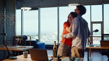 Boş ofiste dans eden sarhoş iş arkadaşları. Gülümseyen güzel bir kadın, yakışıklı bir adama sevgiyle bağlanıyor. Romantik çift panoramik odada şampanya bardaklarıyla müzik dinleyip eğleniyor. 