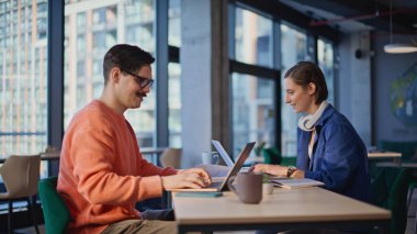 Pozitif çalışanlar ofisteki ortak çalışma alanında beş başarılı ekip çalışması yapıyor. Dizüstü bilgisayarların başında çalışan gülümseyen kadın proje hedeflerine ulaşma sevinci içinde. Mutlu meslektaşlar.