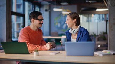 Arkadaş canlısı iş arkadaşları kahve fincanlarını tokuşturarak yaratıcı ajans iş yerinde yakın planda konuşuyorlar. Ara veren gülümseyen kadın çalışma alanını paylaşıyor. Gayri resmi sohbetin keyfini çıkaran mutlu meslektaşlar.