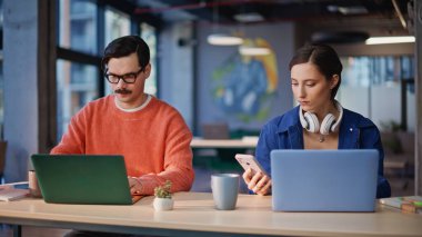 Modern kafeteryada dizüstü bilgisayar arayan iki öğrenci. Birlikte çalışan bilgisayarlarda çalışan ciddi serbest çalışanlar. İş yerinde online araştırma yaratıcı pazarlama stratejisi hazırlayan ekip üyeleri