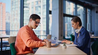 İki serbest çalışan, yakın çekim alanında konuşuyorlar. Kahve fincanı alan gülümseyen bıyıklı adam ofisteki dost canlısı bayan meslektaşla konuşuyor. İş yerinde işe ara veren yaratıcı takım arkadaşları.