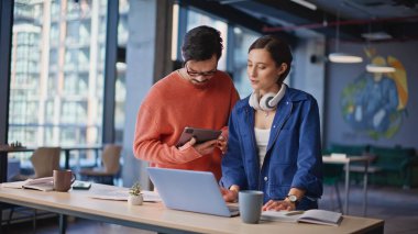 İki girişimci iş kurma konusunda beyin fırtınası yapıyor ortak çalışma ofisindeki bilgisayarlara bakıyorlar. Profesyonel erkek kadın birlikte iş düşünür. Şirket meslektaşları zor proje konusunda işbirliği yapıyorlar.