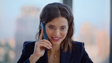 Şirket lideri, akıllı telefondan modern ofiste iş anlaşmasını konuşuyor. İş yerinde cep telefonuyla görüşen gülümseyen iş kadını portresi. Başarılı yönetici telefon danışmanlığı.