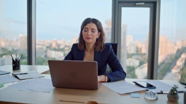 Ofis çalışanı dizüstü bilgisayarda modern çalışma alanlarını tarıyor. Motivasyonsuz kadın yönetici, bilgisayar kapağını kapatıyor ve ağır iş görevleri altında eziliyor. İş yerinde proje üzerinde düşünmekten yorulmuş zarif bir iş kadını..