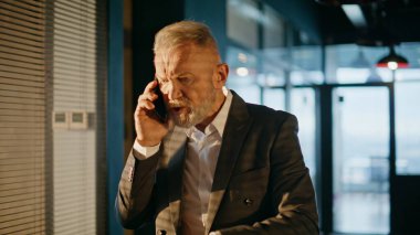 Gün batımı koridorunda el kol hareketleri yapan bir işadamı cep telefonu kavgası yapıyor. Sinirli kıdemli girişimci akıllı telefondan endişeli diye bağırıyor. Kızgın yöneticinin işi bitti. Koridorda stres var..