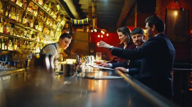 Mutlu iş adamları gece barında garsonun içki siparişi verdiğini konuşuyor. Neşeli müşteriler parti kulübünde barmenle sohbet etmek için kokteyl soruyorlar. Kurumsal insanlar birlikte dinleniyorlar. 