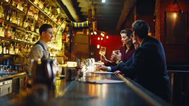 Gece kulübünde içki içen üç arkadaş. İş arkadaşları akşam barında kokteyl içerken gülüyorlar. Neşeli müşteriler kafede takım için alkol istiyor. İnsanlar partide garsonun dinlendiğini söylüyor.