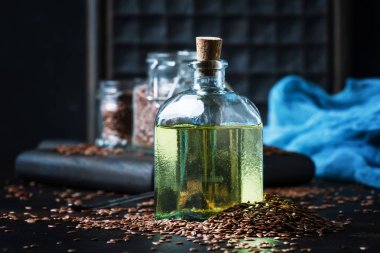 Cam şişe ve tohum, koyu arka plan, seçici odak içinde keten tohumu ya da keten yağı