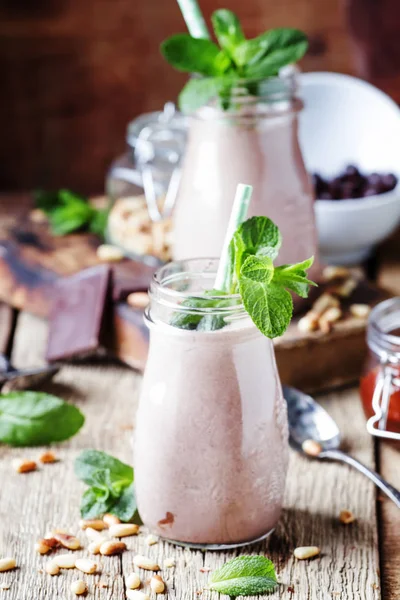 Chocolate-mint creamy smoothies in bottles on an old wooden background, selective focus